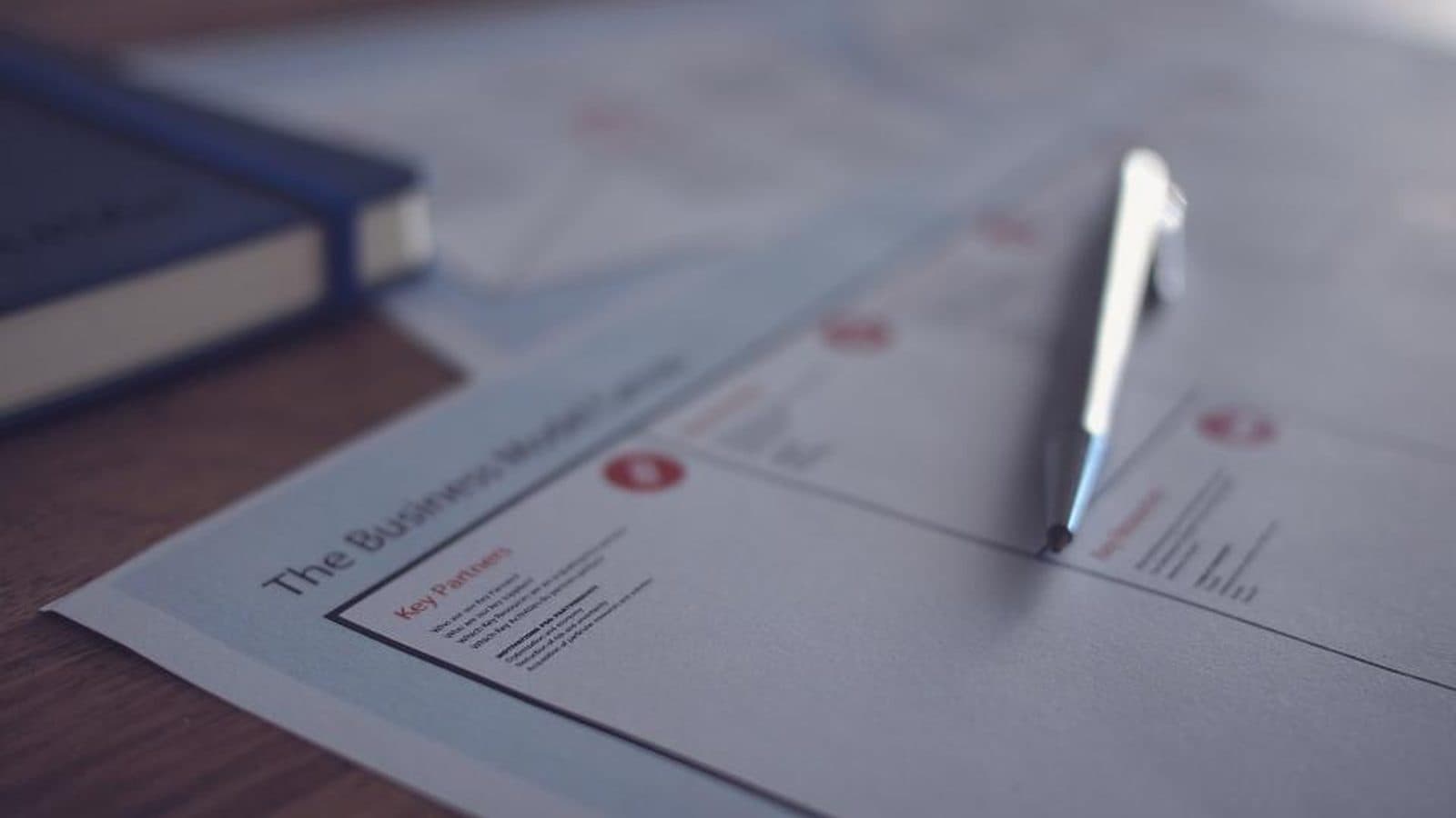 A close view of a printed document and a pen resting on a bound report.