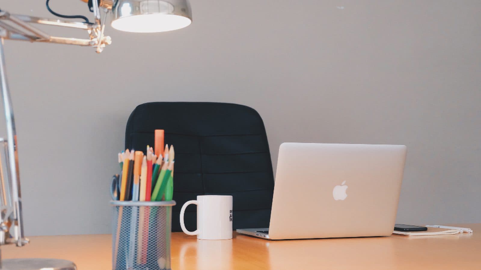 A tidy desk with a laptop, notebook and desk lamp used for electronic document review.